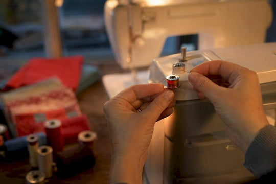 Hands winding thread onto a sewing machine bobbin