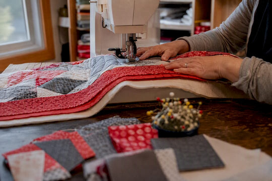 Hands guiding quilt layers under walking foot