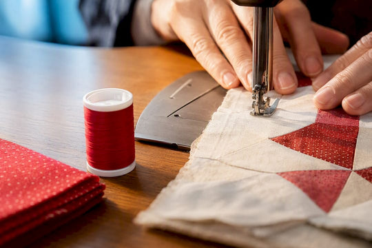 Quilter guiding cotton thread through pieced seam