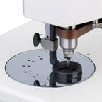 Industrial sewing machine single-needle area with presser foot and round throat plate on white body