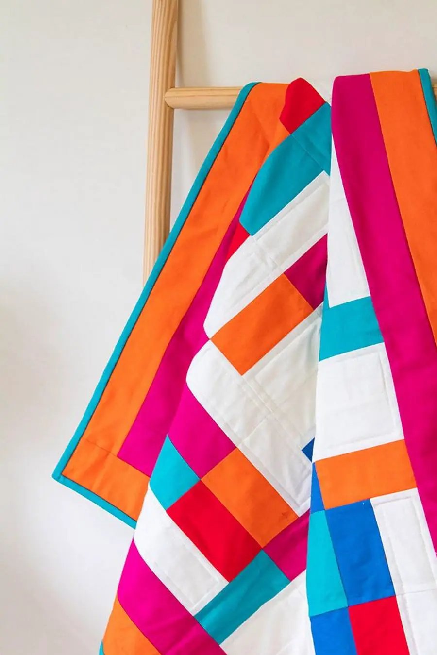 Crafters Companion Threaders Shape Creator cutting mats, a colorful color-block quilt draped on a wooden ladder