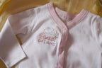 Baby pink long-sleeve onesie with embroidered design reading Sweet Dreams and small star accents