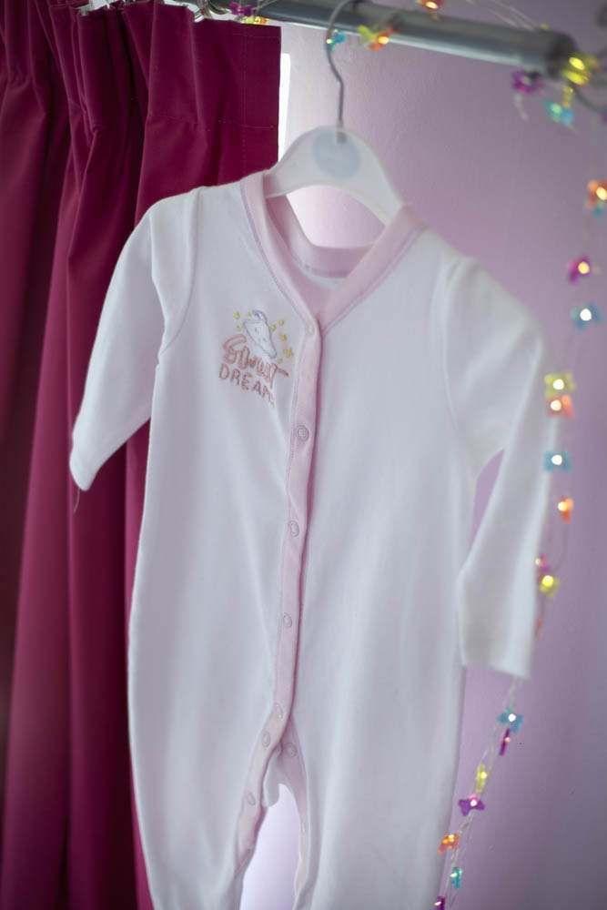 Threaders Embroidery Transfer Sheets - Baby: white baby onesie with pink trim on a hanger, embroidered chest.