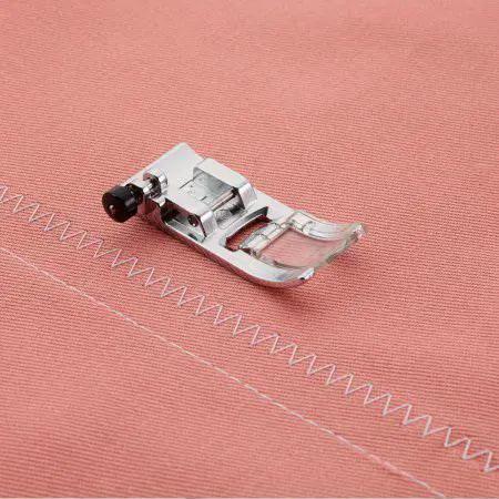 Sewing presser foot attachment on pink fabric with zigzag stitch