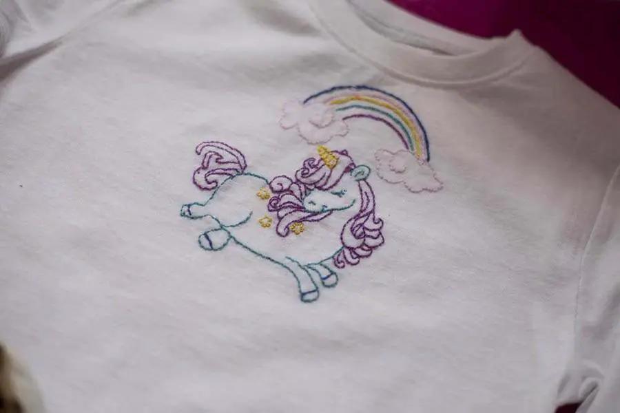 Threaders embroidery transfer sheets, fantasy design on white shirt featuring a colorful unicorn under a rainbow