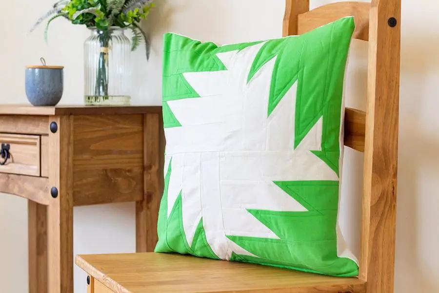Threaders cushion on a wooden chair featuring a bright green and white geometric pattern