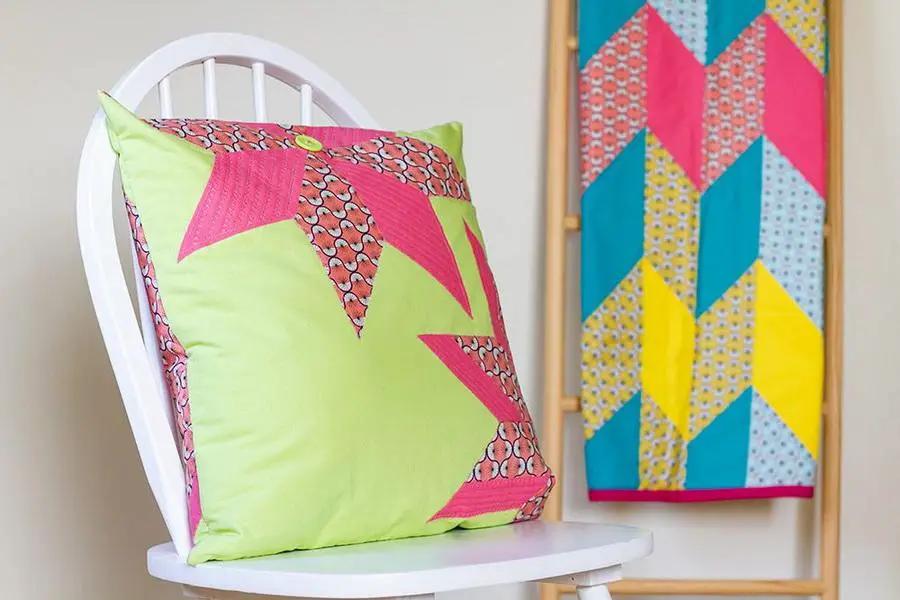 Crafters Companion Threaders Shape Creator cutting mats; lime-green pillow on white chair with a geometric wall quilt.