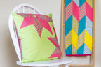 Crafters Companion Threaders Shape Creator cutting mats; lime-green pillow on white chair with a geometric wall quilt.