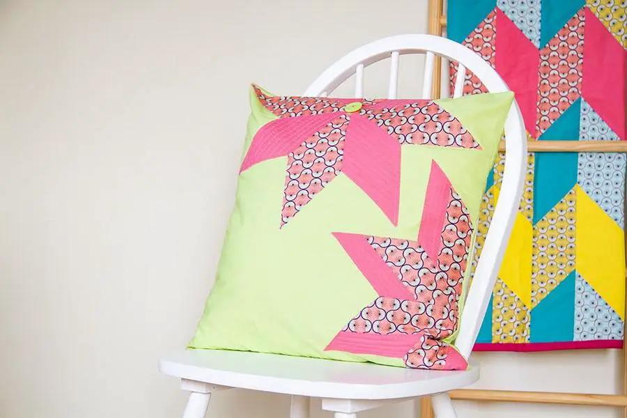 Threaders Shape Creator cutting mats; lime-green pillow with pink patchwork on a white chair, bright quilt backdrop