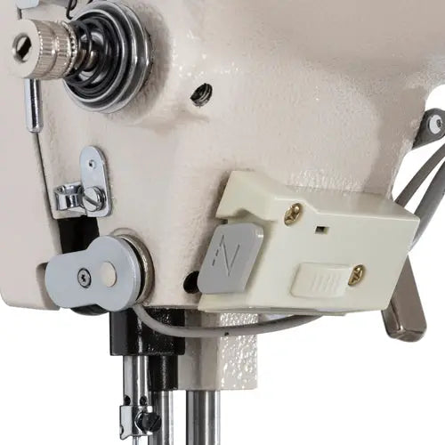 Industrial sewing machine head in beige with control box.