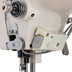 Industrial sewing machine head in beige with control box.