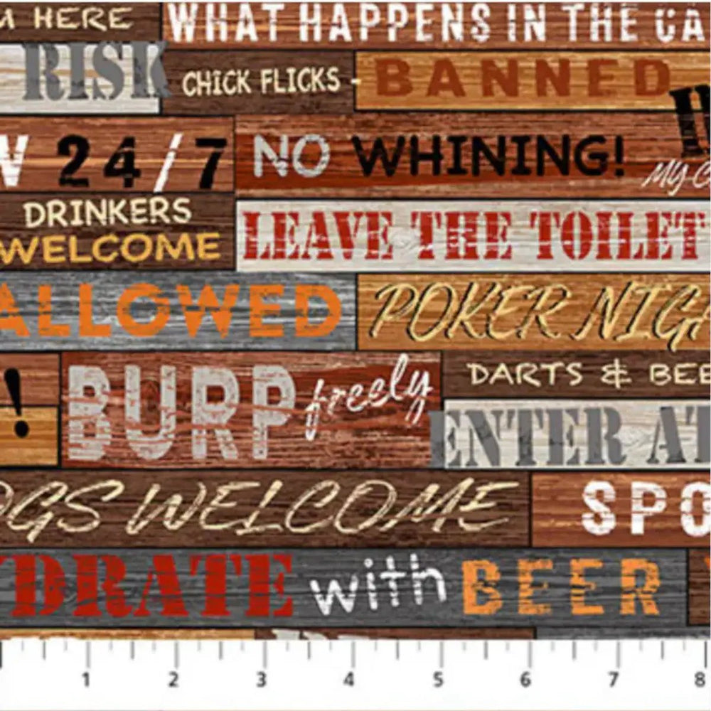 The Cave Words tan multi quilting fabric with humorous man cave phrases and rustic woodgrain background by Northcott