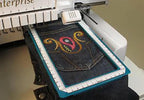 Embroidery hoop DIME Quick Snap 2.0 on an embroidery machine, denim in a turquoise frame with white ruler guides