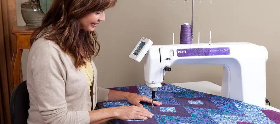 Pfaff PowerQuilter 16.0 long-arm quilting machine in white with purple label, quilting a quilt.