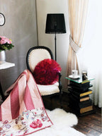 Husqvarna Viking Amber S100 serger machine in a stylish sewing room with a vintage cream chair and red ruffle pillow.