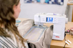 Bernette B59 sewing and embroidery machine; white unit with embroidery hoop on a wooden table.