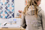 Bernette B59 white sewing and embroidery machine on a wooden worktable in a cozy sewing room.