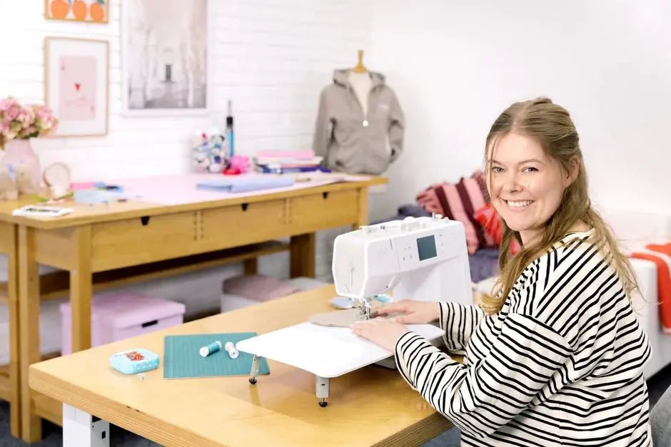 Bernette B57 sewing machine in white on a wooden table with a smiling woman in a striped shirt.