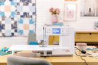 Bernette B57 sewing machine, white, on a wooden table in a sewing room.