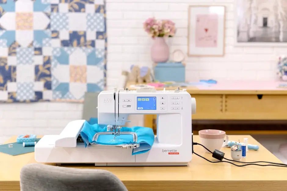 Bernette B59 sewing and embroidery machine, white with blue touchscreen display on a wooden desk.