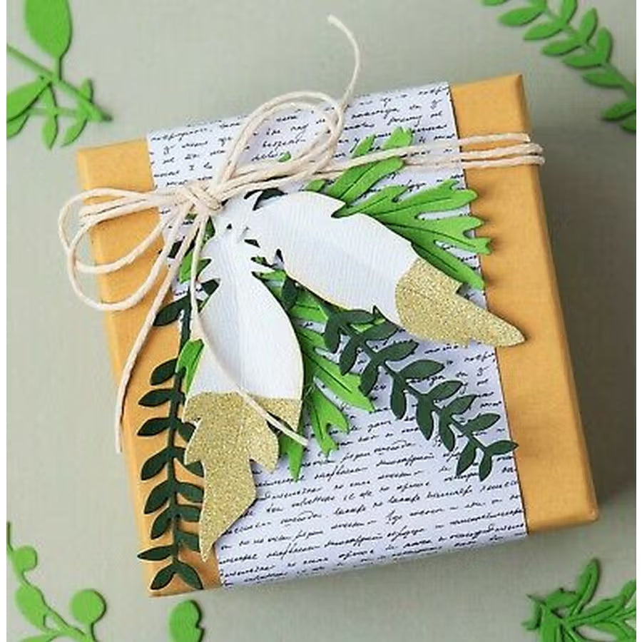 Sizzix Bigz Die Natural Feathers by Jenna Rushforth, white feather shapes with gold glitter tips and green foliage.