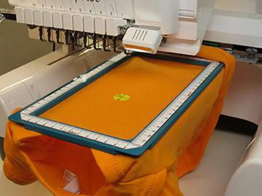DIME Quick Snap 2.0 embroidery hoop on an embroidery machine with orange fabric secured in a blue frame