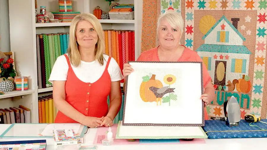 Autumn Love Sew Along Kit class; two women showcase a framed autumn quilt block amid colorful fabrics