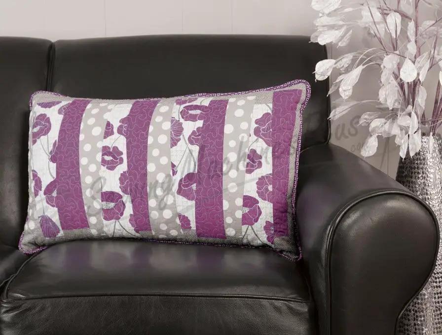 Throw pillow with purple and gray striped pattern on a black leather sofa.