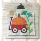 Autumn Love Sew Along Kit by Riley Blake Designs; quilted wall art with pumpkin wagon and teal flowers on plaid.