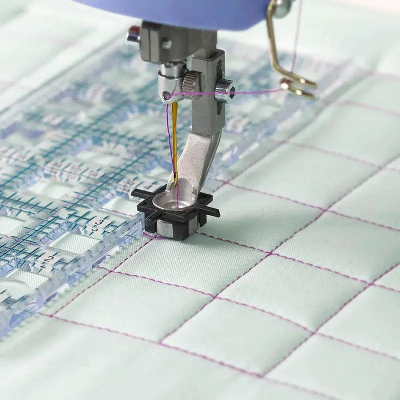 Q'nique Quilt Perfect Ruler Kit presser feet set with purple thread and clear ruler on quilted fabric.