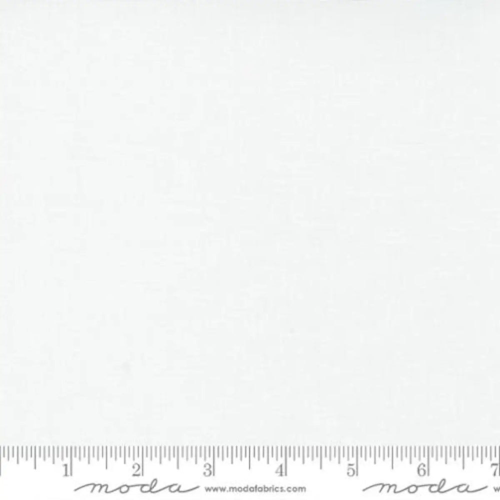 Moda Bella Solids Bleached White PFD quilting cotton fabric with clean white surface and ruler for scale.
