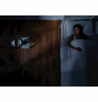 Dyson AM06 10-inch desk fan, white bladeless design beside a bed in a dim room