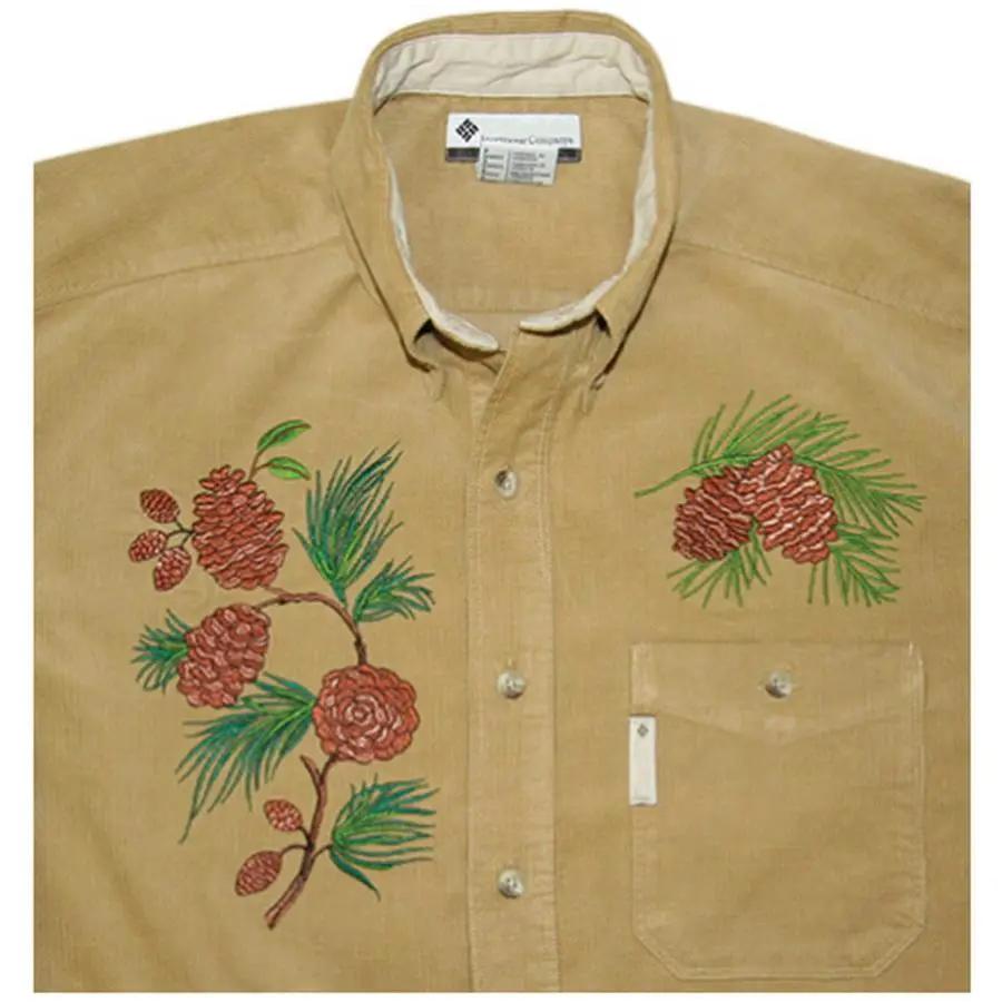 Anita Goodesign Northwoods embroidery design on tan button-down shirt with pinecone motifs
