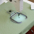 Free Motion Grip Works w/Stitch Regulator CNFMG on green quilted fabric beneath a sewing machine