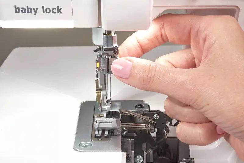 Baby Lock Serenity 4-Thread Serger sewing machine; white body with hands threading the needle.