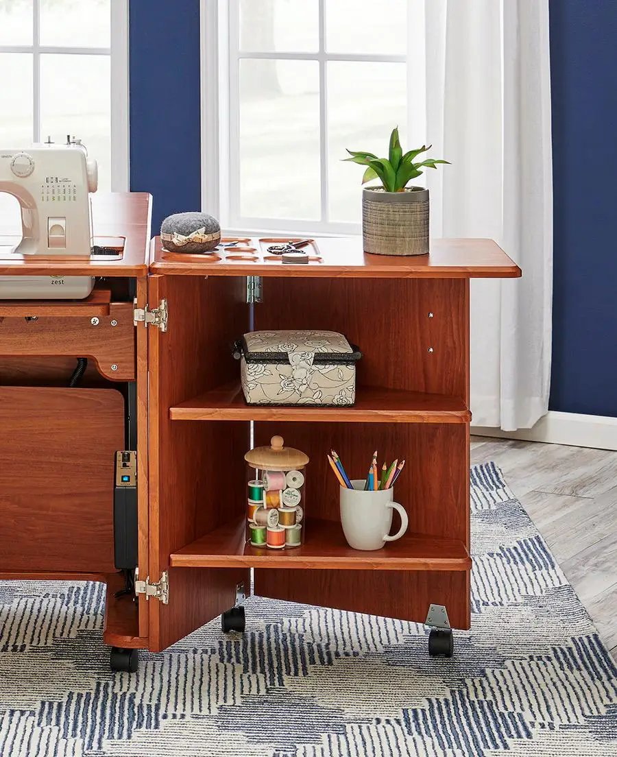 Koala Studios Heritage Cub sewing cabinet in teak, on casters, with sewing machine and storage shelves.