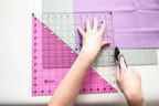 Crafters Companion Threaders A2 cutting mat; pink base with clear overlay and a rotary cutter in use.