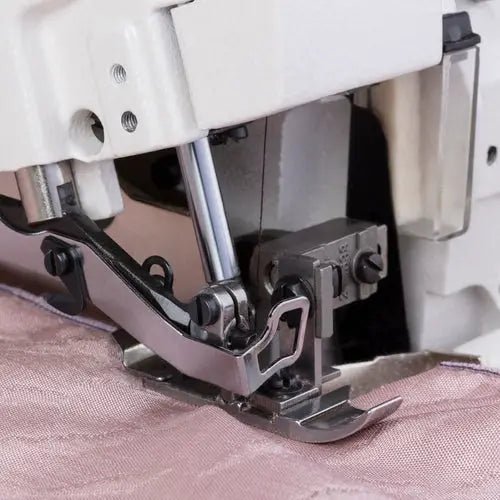 Consew CM793 serger with assembled table and servo motor; close-up of presser foot on pink fabric.