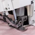 Consew CM793 serger with assembled table and servo motor; close-up of presser foot on pink fabric.