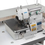 Consew CM793 serger with assembled table and servo motor; white industrial overlock with green thread spools.
