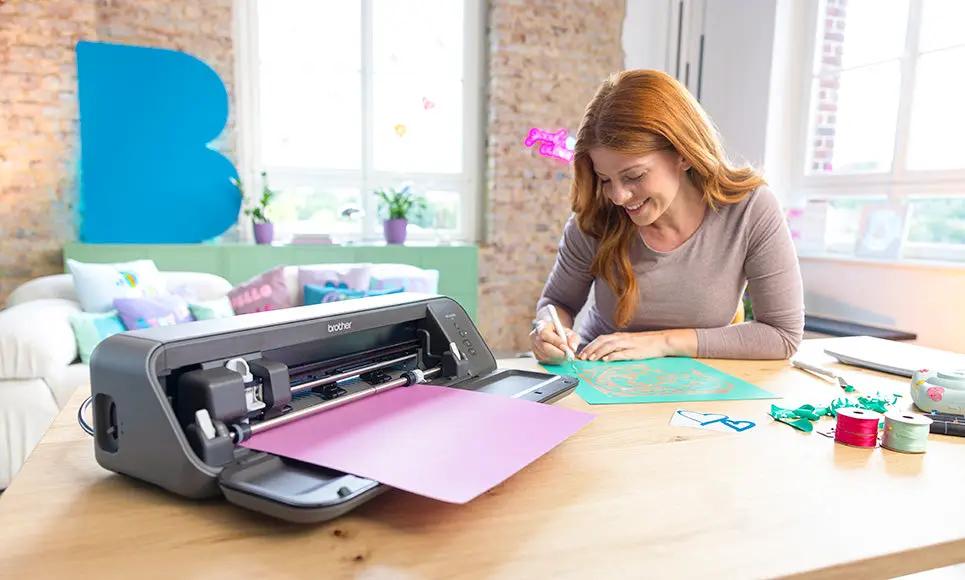 Brother Bellissimo CT1 cutting machine, gray craft cutter on desk with pink and turquoise papers