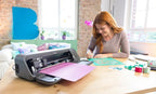 Brother Bellissimo CT1 cutting machine, gray craft cutter on desk with pink and turquoise papers