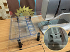 Sew Steady Clear Ruler Work Glider; transparent acrylic grid ruler with blue edges.