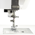 Janome Continental M6 sewing machine needle area with metal presser foot on the plate.