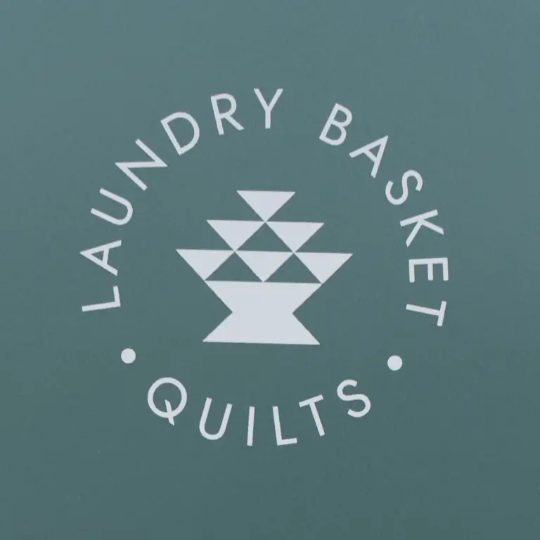 Laundry Basket Quilts logo on teal background, circular text around a geometric white emblem.