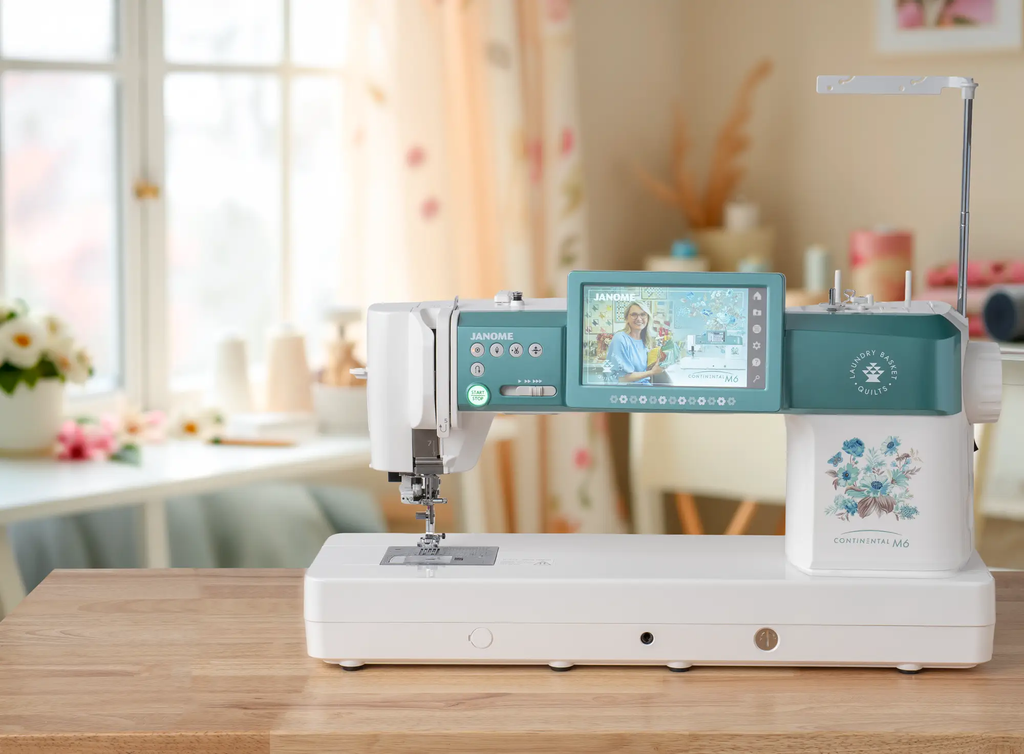 Janome Continental M6 sewing machine with teal body on a white stand