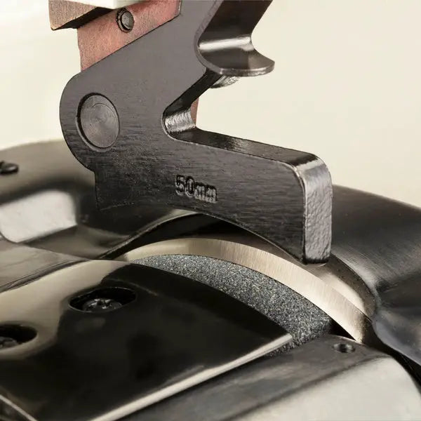 Skiving machine component in black metal with 50mm marking, close-up of clamp area on table
