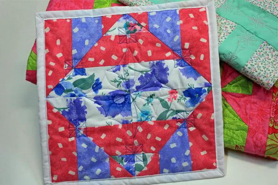 DIME Windmill Garden Quilt, quilting accessory with red and blue patchwork floral blocks and white border