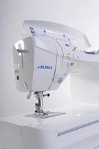 Juki HZL-DX7 sewing machine, computerized white unit with blue logo, side view.