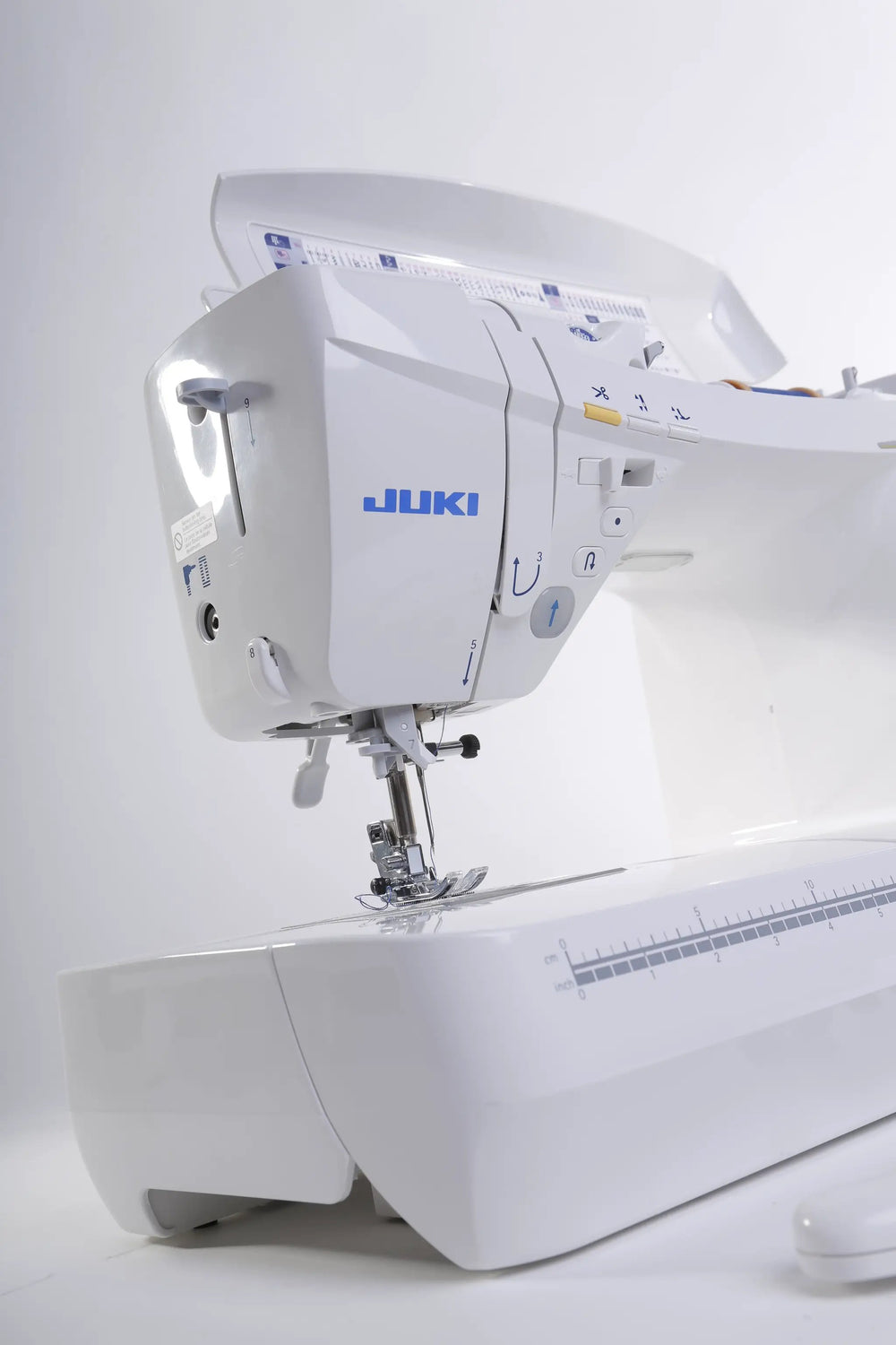 Juki HZL-DX7 computerized sewing machine, white with blue branding, side view.